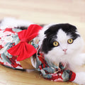 Black and white cat wearing Makuro's kimono in red floral print with a big red bow
