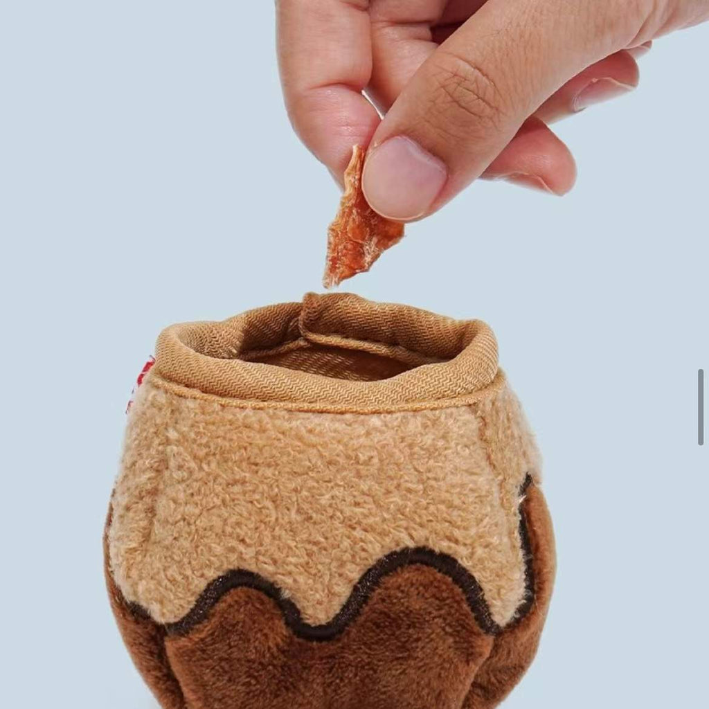 Hand tucking a treat into the pocket of the plush takoyaki snuffle toy