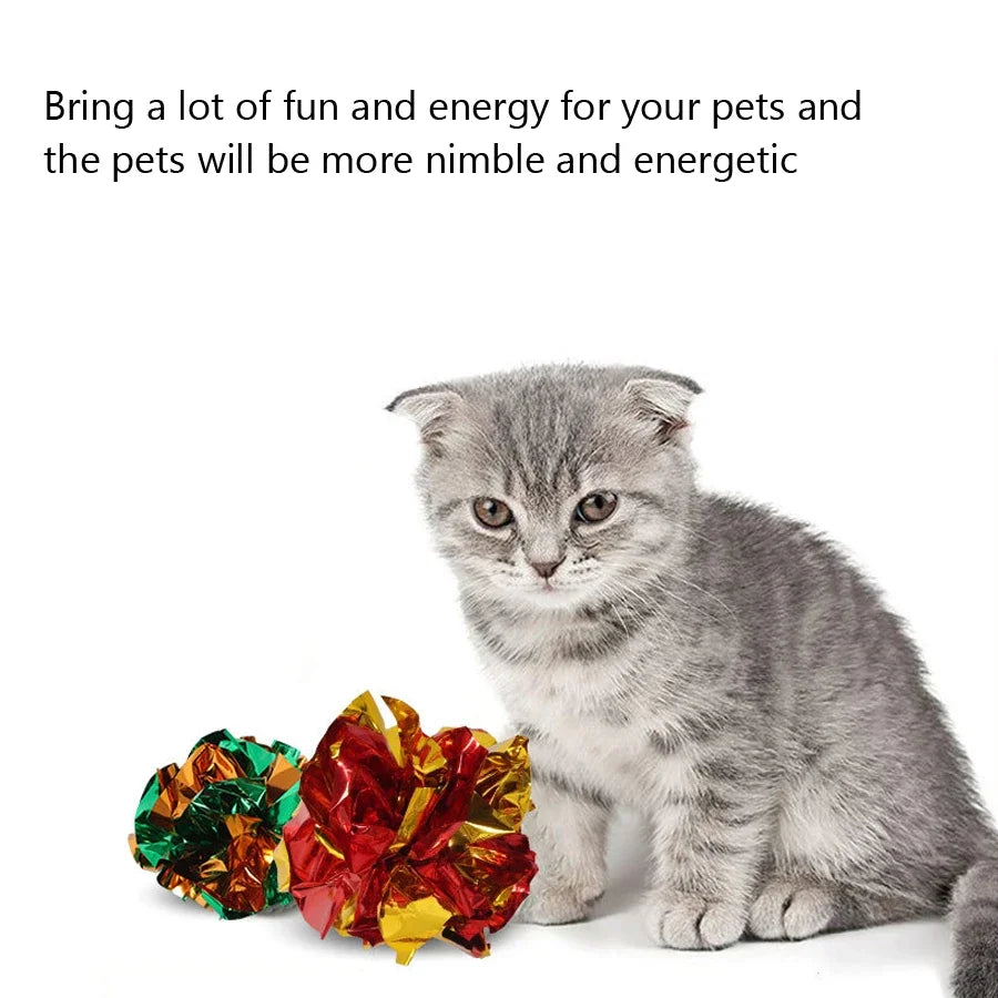 Grey kitten sitting next to two shiny crinkle balls
