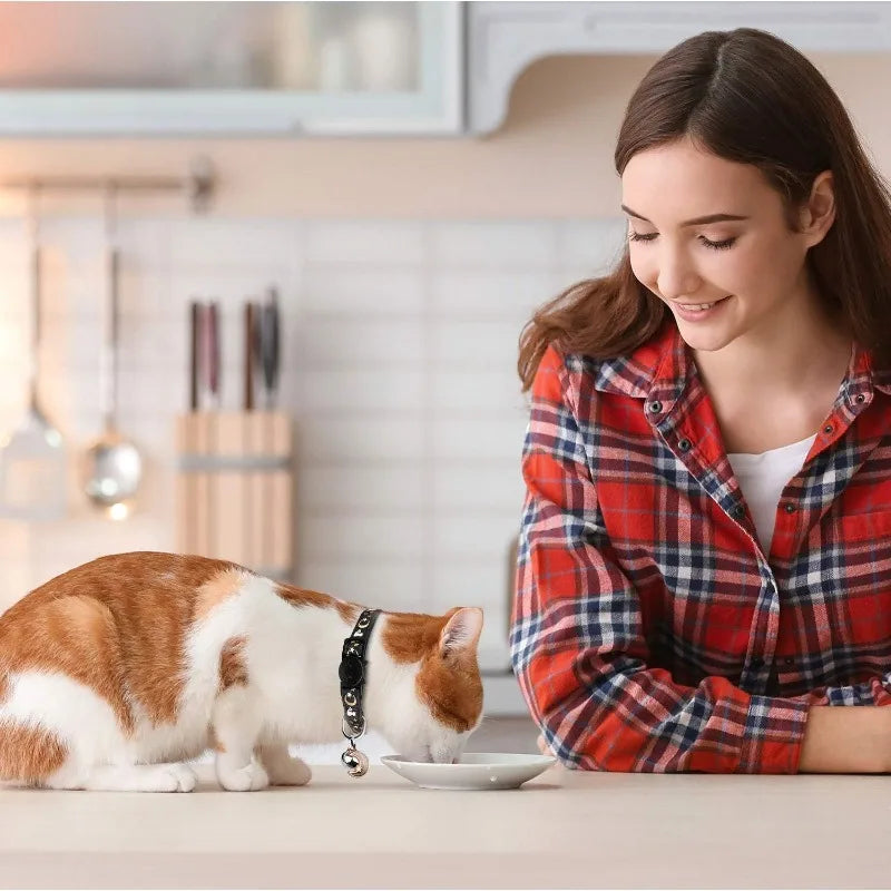 Ginger and white cat eating while wearing the black glow collar