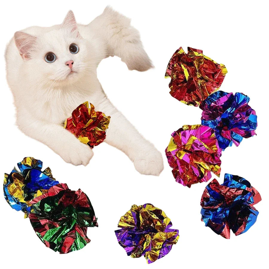 White cat batting a pile of shiny mylar crinkle balls