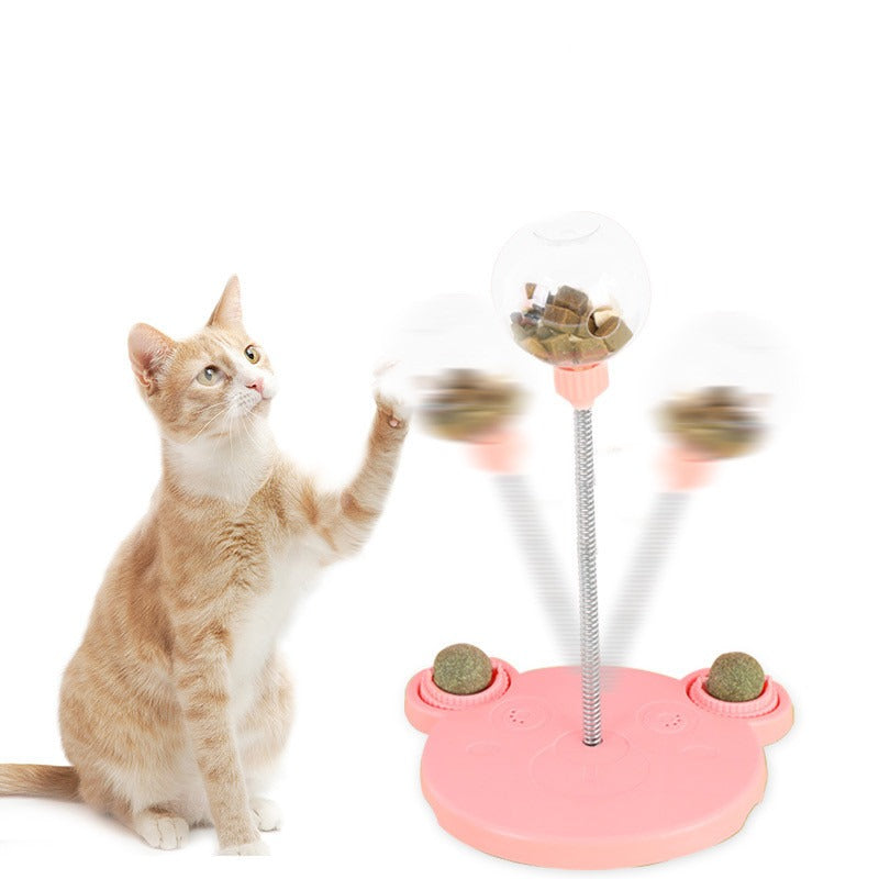 Cat swatting the wobbling pink treat ball as it swings on its spring